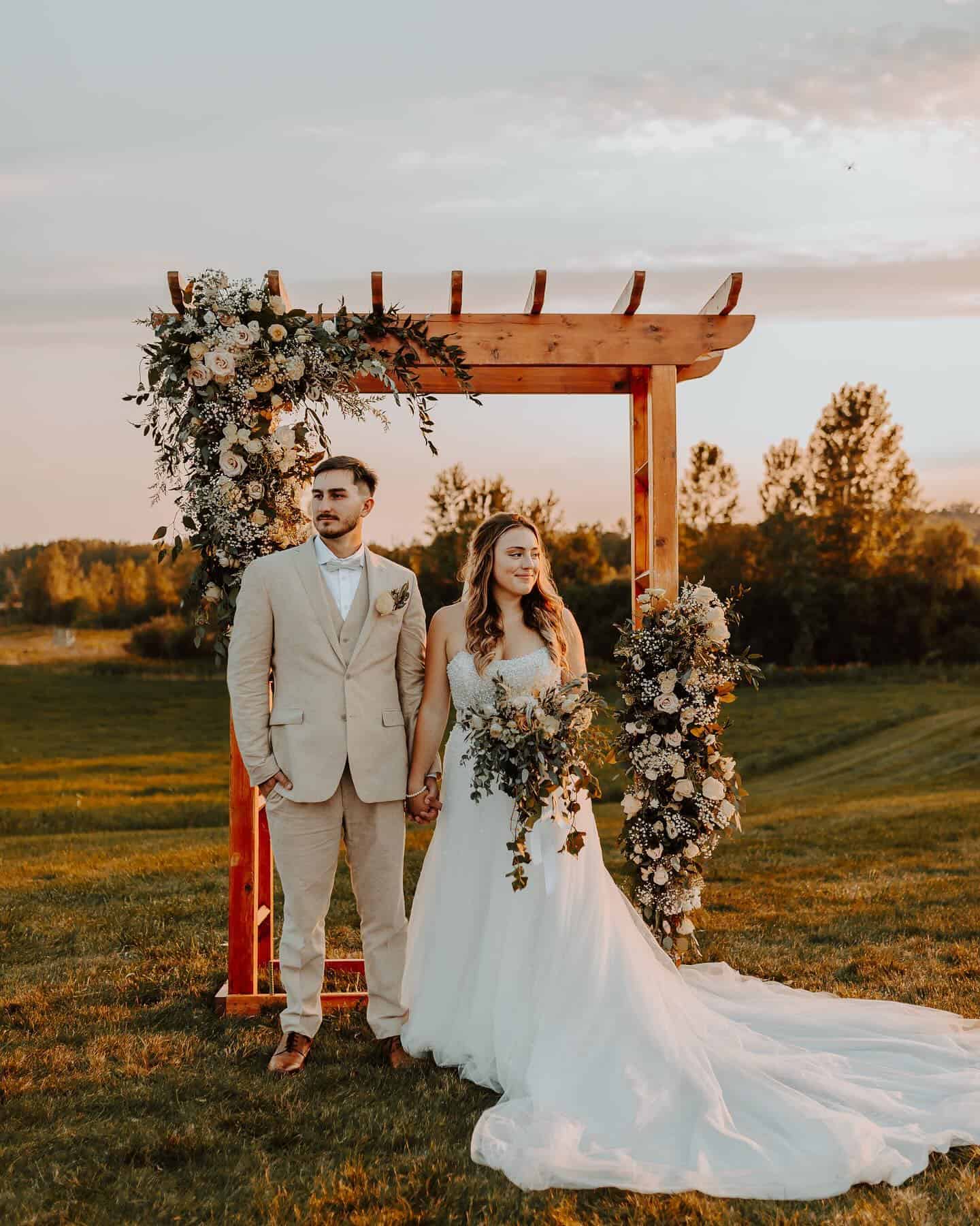 Wedding ceremony at Dellwood Barn with floral arch backdrop.