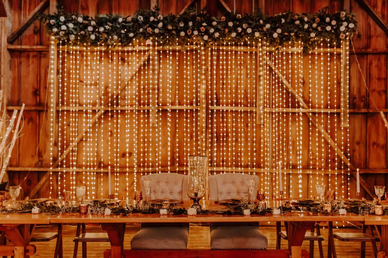 Wedding reception decor at Dellwood Barn featuring string lights and floral arrangements for rustic.