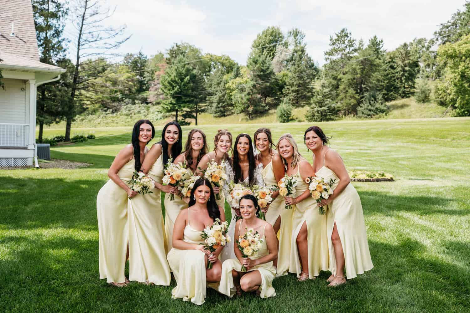 Bridesmaids in matching yellow dresses holding bouquets at Dellwood Barn wedding.