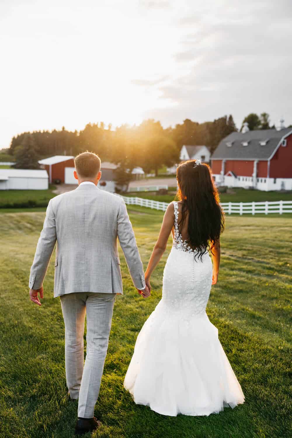 Romantic couple walking hand-in-hand at Dellwood Barn wedding venue during sunset.