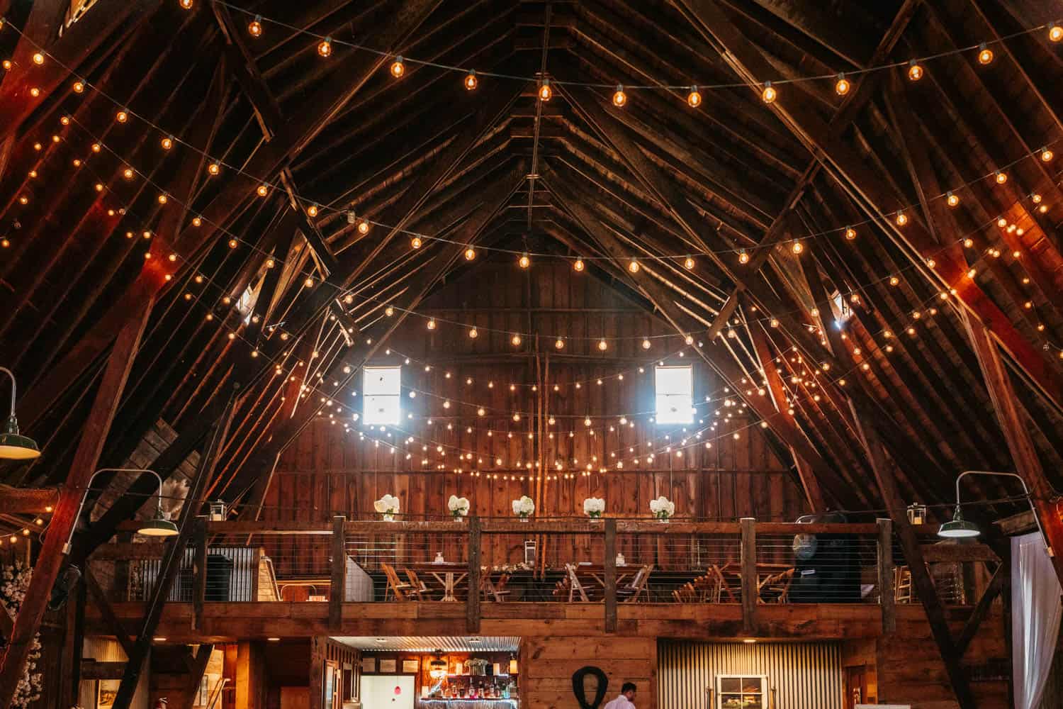 Barn wedding reception with string lights and rustic decor.